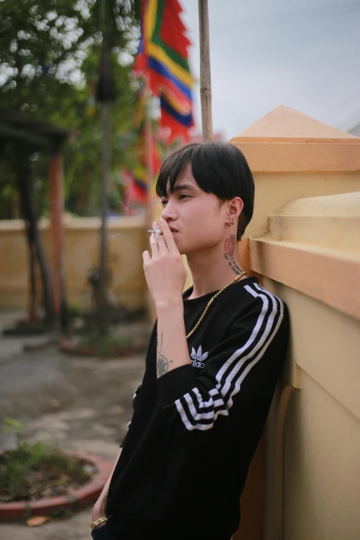 a man leaning against a wall smoking a cigarette, an album cover, inspired by Gang Hui-an, trending on pexels, realism, beautiful androgynous girl, vietnamese woman, 1 7 - year - old boy thin face, instagram photo