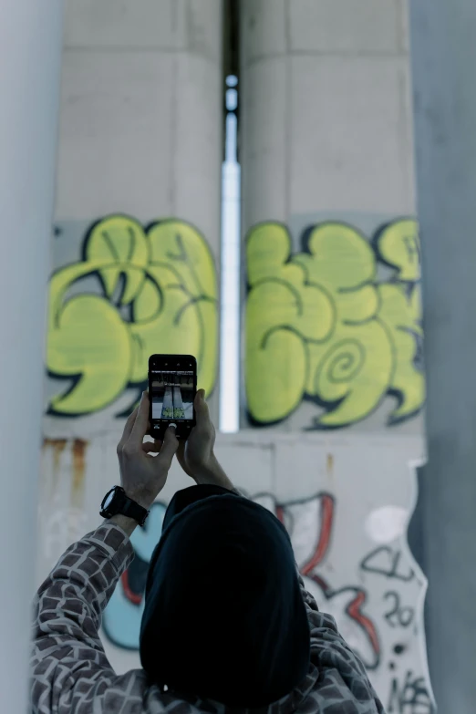 a person taking a picture of a graffiti covered wall, looking down on the camera, technologies, without text, multiple stories