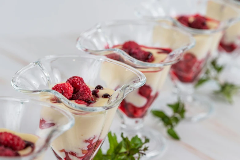 a row of desserts sitting on top of a table, raspberry, high quality product image”, glassware, manuka