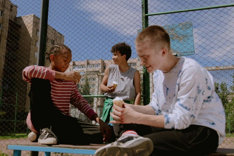 a group of young men sitting on top of a blue bench, by Emma Andijewska, pexels contest winner, graffiti, people on a picnic, lil peep, on a sunny day, film still promotional image