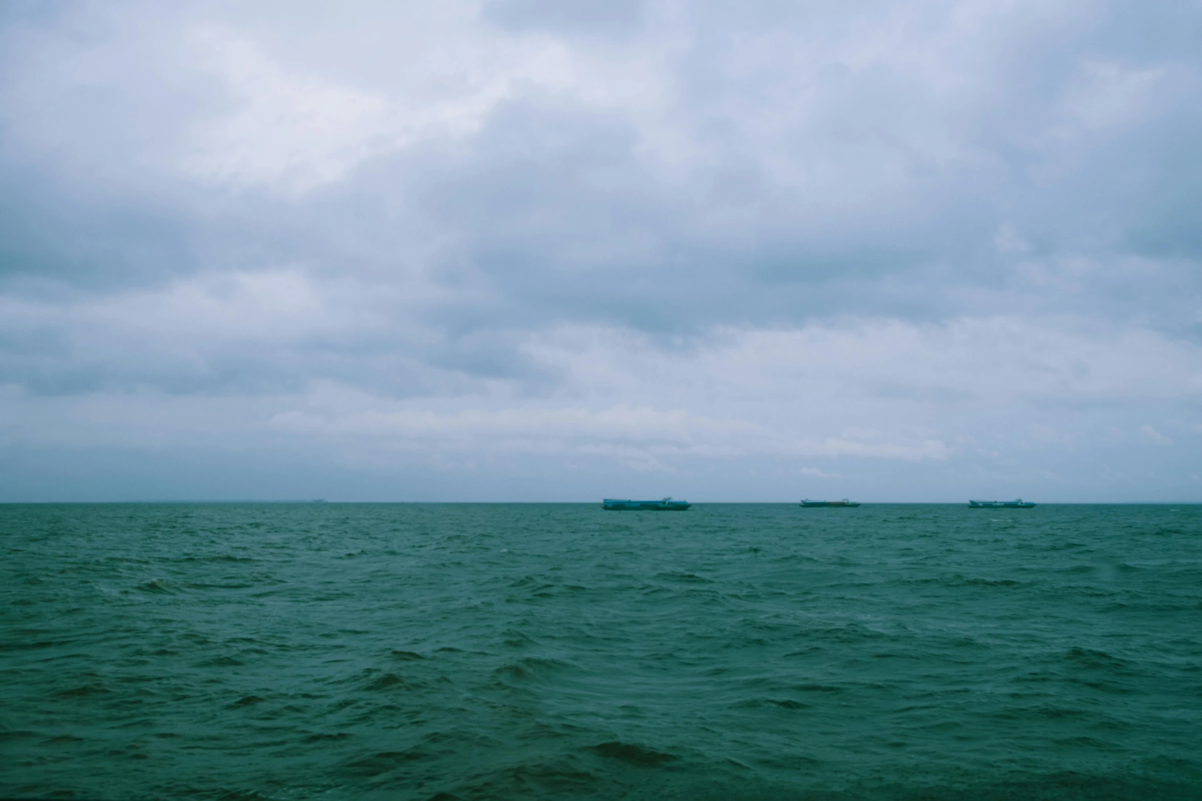 a large body of water under a cloudy sky, by Attila Meszlenyi, unsplash, shipfleet on the horizon, cyan and green, low quality photo, shot on hasselblad