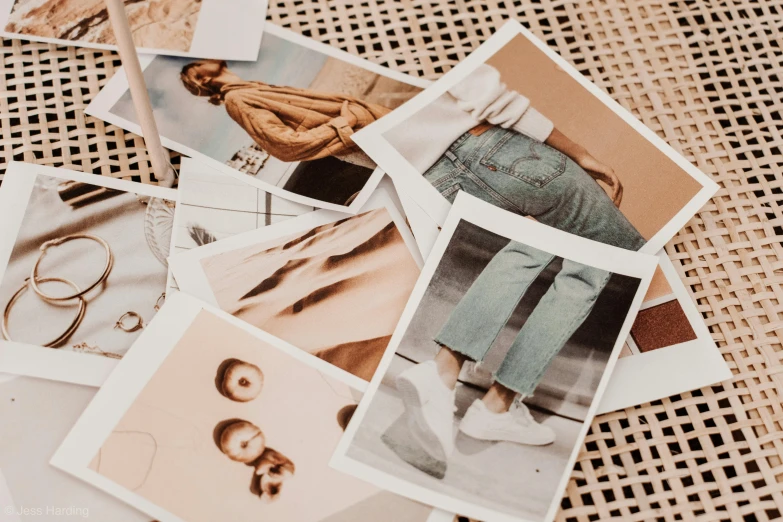 a pile of photos sitting on top of a table, by Emma Andijewska, trending on pexels, jeans, beige colors, illustration art, modeling photography