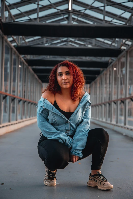 a woman squatting down on a bridge, an album cover, trending on pexels, curly red hair, riyahd cassiem, plus-sized, casual pose