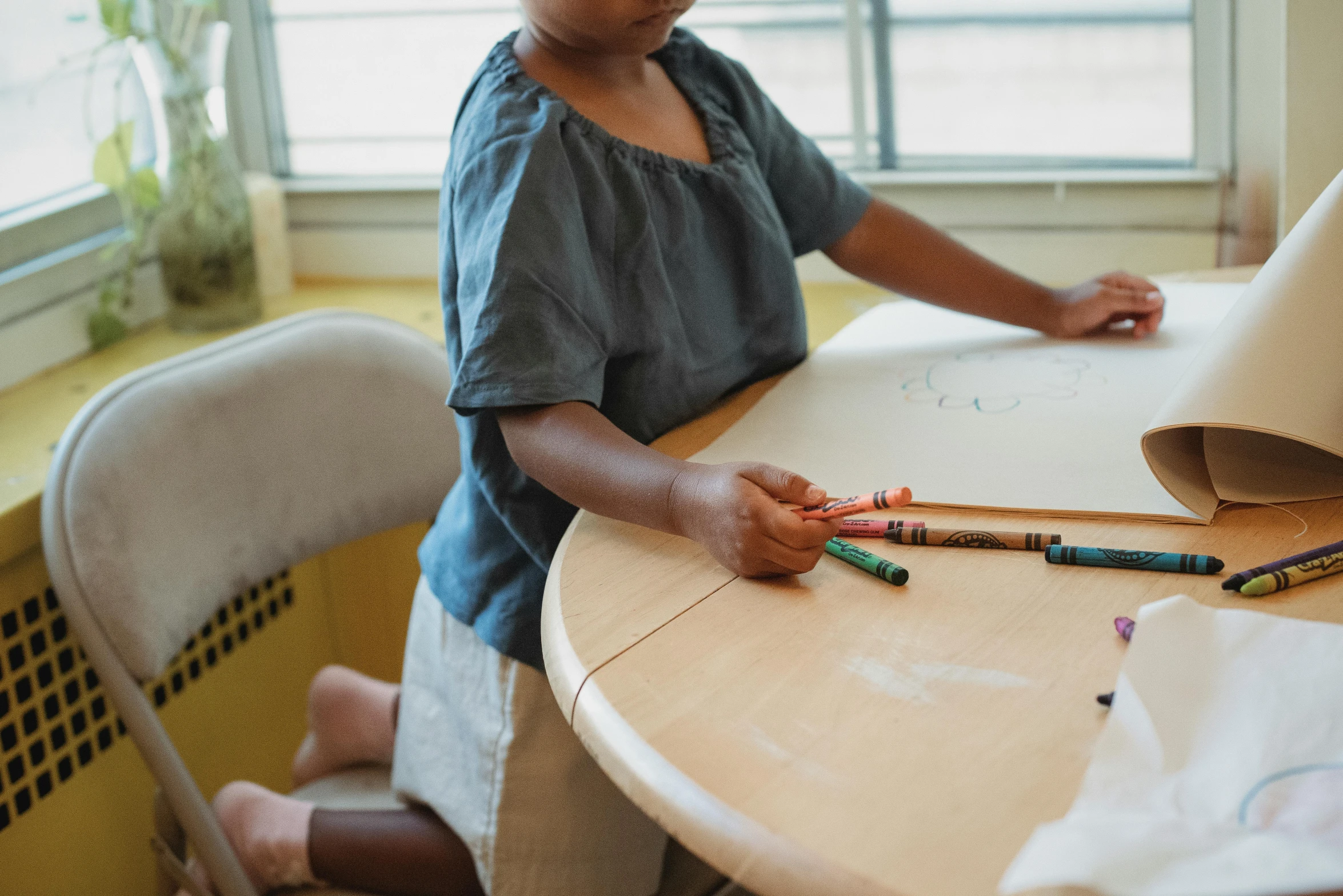 a little girl sitting at a table with crayons, by Arabella Rankin, pexels contest winner, te pae, whiteboards, sitting on top a table, riyahd cassiem