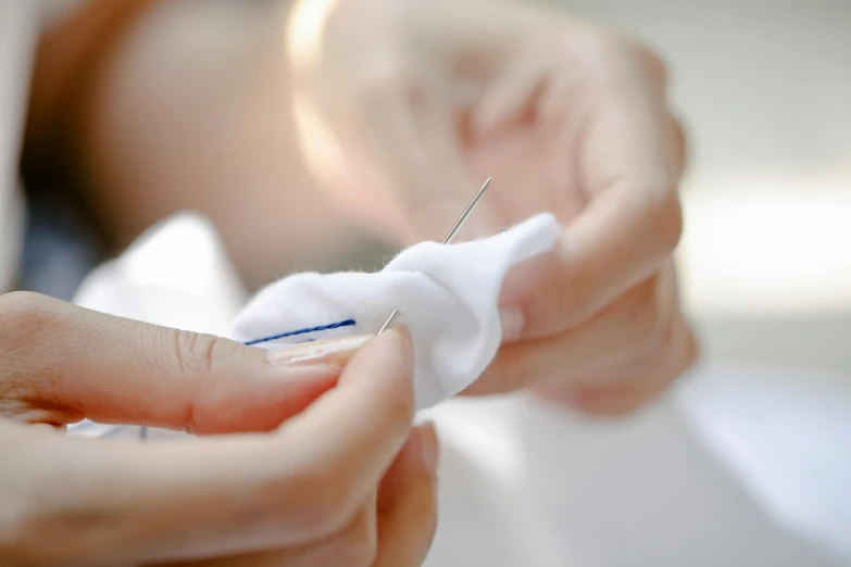 a close up of a person holding a needle, white cloth