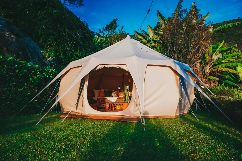 a tent sitting on top of a lush green field, everything enclosed in a circle, shambala, light tan, maui