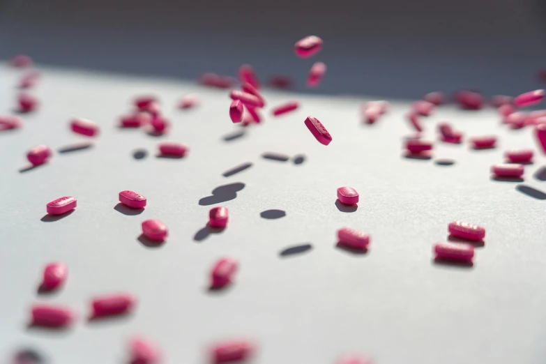 a table topped with lots of pink pills, a microscopic photo, by Emma Andijewska, unsplash, plasticien, plexus, scattered, red emerald, opening shot