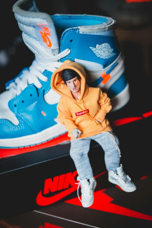 a person sitting on top of a pair of shoes, an album cover, inspired by Jordan Grimmer, unsplash, hyperrealism, highly detailed toy, justin bieber, wearing a blue hoodie, r / paintedminis