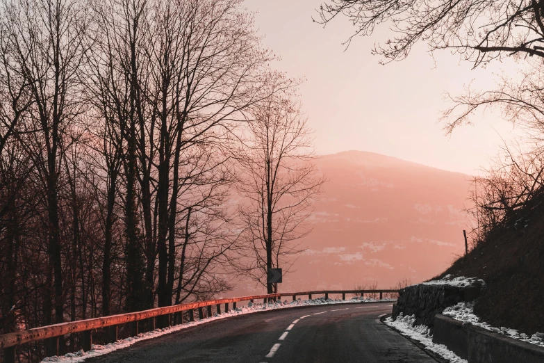 a road with trees on both sides and a mountain in the background, pexels contest winner, orange / pink sky, winter, curving, thumbnail