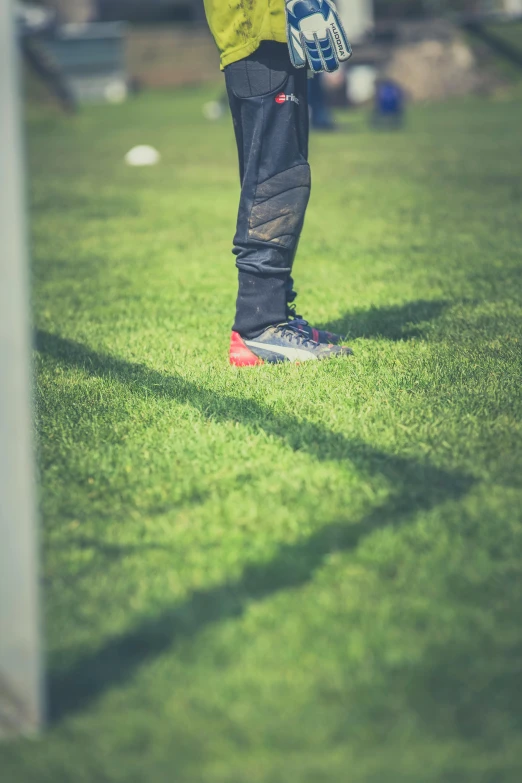 a person standing on a soccer field holding a soccer ball, by Jan Tengnagel, pexels, 15081959 21121991 01012000 4k, he has boots, hiding behind obstacles, soft shadow