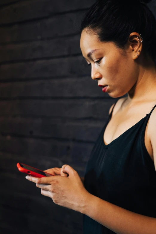 a woman is looking at her cell phone, trending on pexels, red on black, half asian, slightly turned to the right, 1450