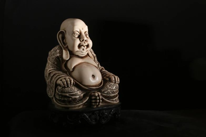 a buddha statue sitting on top of a table, a statue, featured on zbrush central, cloisonnism, shot on hasselblad, intricately carved antique bone, an anthropomorphic stomach, with a black background
