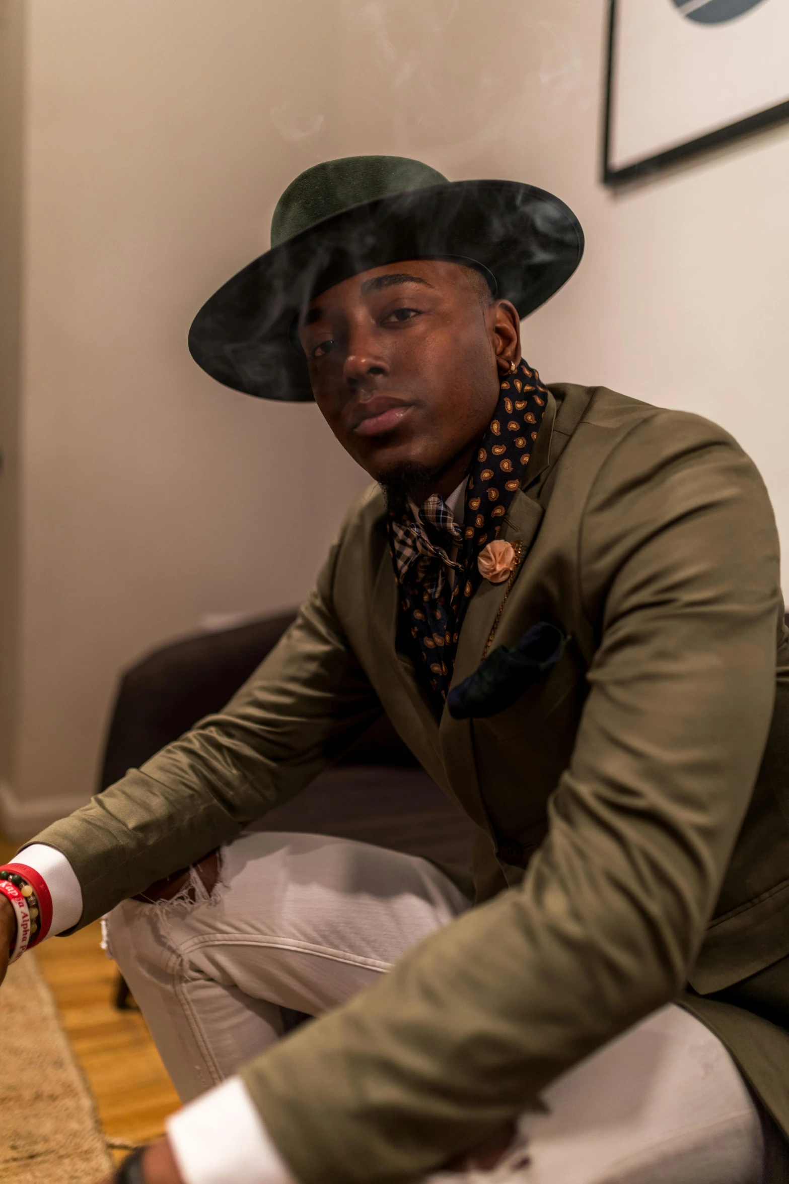 a man in a hat sitting on a couch, inspired by Charles Martin, trending on pexels, afrofuturism, beautiful androgynous prince, lapel, standing elegantly, uk