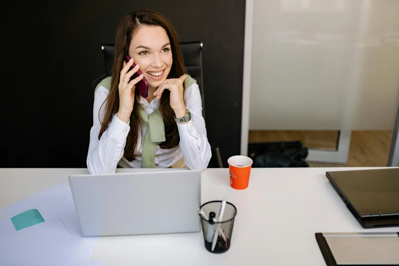 a woman sitting at a desk talking on a cell phone, trending on pexels, very funny, 9 9 designs, low quality photo