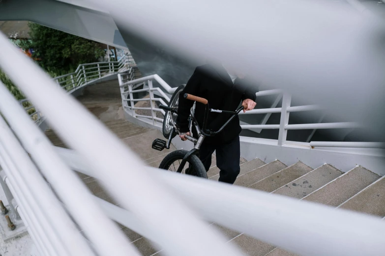 a man riding a bike down a flight of stairs, a picture, unsplash, low quality photo, a man wearing a black jacket, structure : kyle lambert, paisley