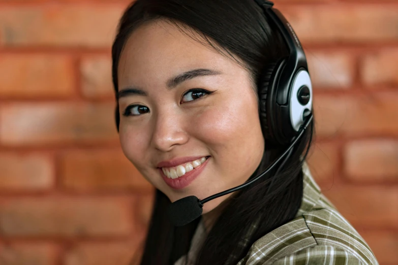 a woman wearing a headset in front of a brick wall, pexels contest winner, hurufiyya, in an call centre office, young cute wan asian face, aussie, background image