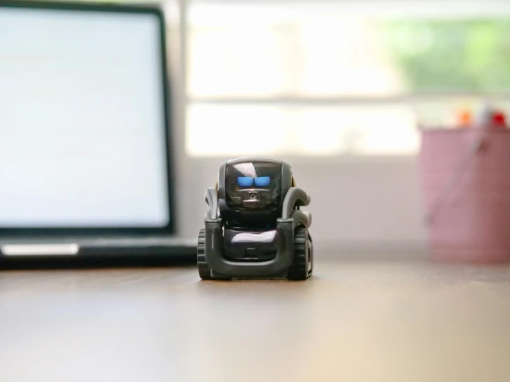 a toy car sitting in front of a laptop computer, scout police robot, sitting across the room, very tiny, photograph taken in 2 0 2 0