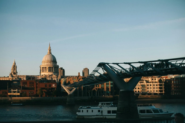 a boat sitting on top of a river next to a bridge, by Christopher Wren, pexels contest winner, with great domes and arches, norman foster, jen atkin, warm light