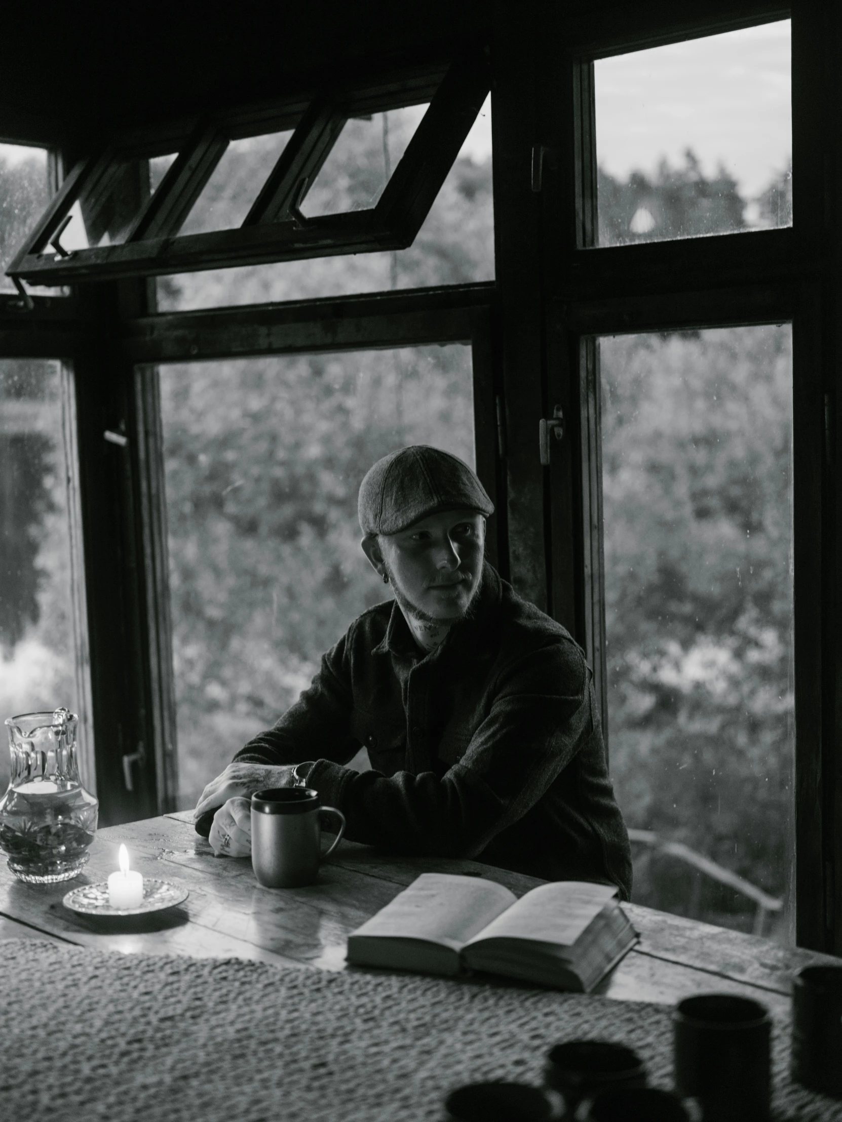 a man sitting at a table in front of a window, by Kurt Seligmann, shin hanga, cottage hippie naturalist, low-light photograph, song nan li, portrait image