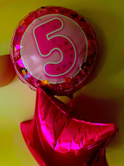 a person holding a balloon with the number five on it, a picture, by reyna rochin, pop art, dora the explorer, foil, pink and red color style, blur:-1