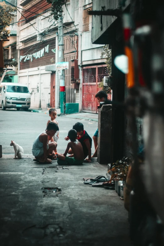 a group of people sitting on the side of a road, by Sebastian Vrancx, pexels contest winner, manila, shady alleys, kneeling, children playing with pogs