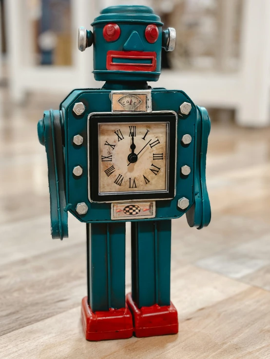 a blue robot clock sitting on top of a wooden table, teal silver red, product display photograph, home display, close - up photograph