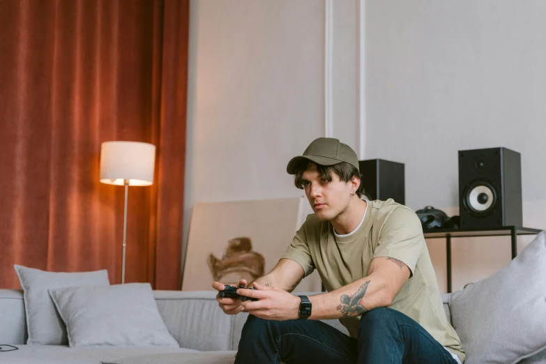 a man sitting on a couch holding a remote control, by Adam Marczyński, trending on pexels, realism, wearing a baseball cap, gaming table, joe keery, sitting across the room