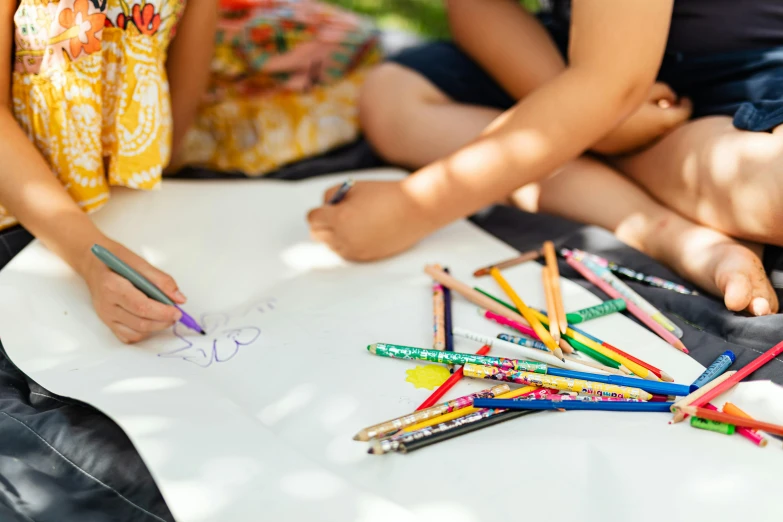 two girls sitting on the ground drawing with colored pencils, a child's drawing, pexels contest winner, al fresco, a close up shot, rectangle, idealised