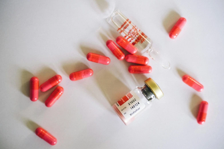 a bunch of red pills sitting on top of a table, by Emma Andijewska, antipodeans, vibrant vials, pink, unedited, mingchen shen