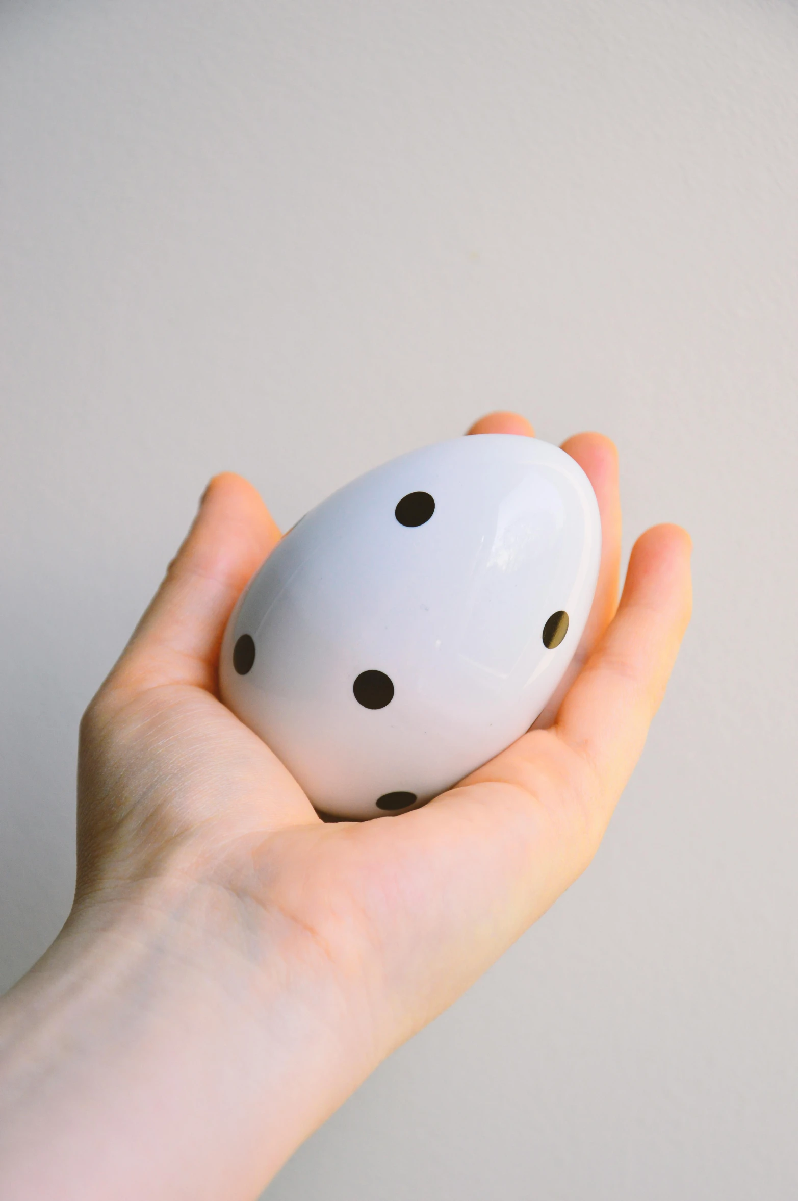 a person holding an egg in their hand, unsplash, visual art, white with black spots, ocarina of time, white plastic, modular item