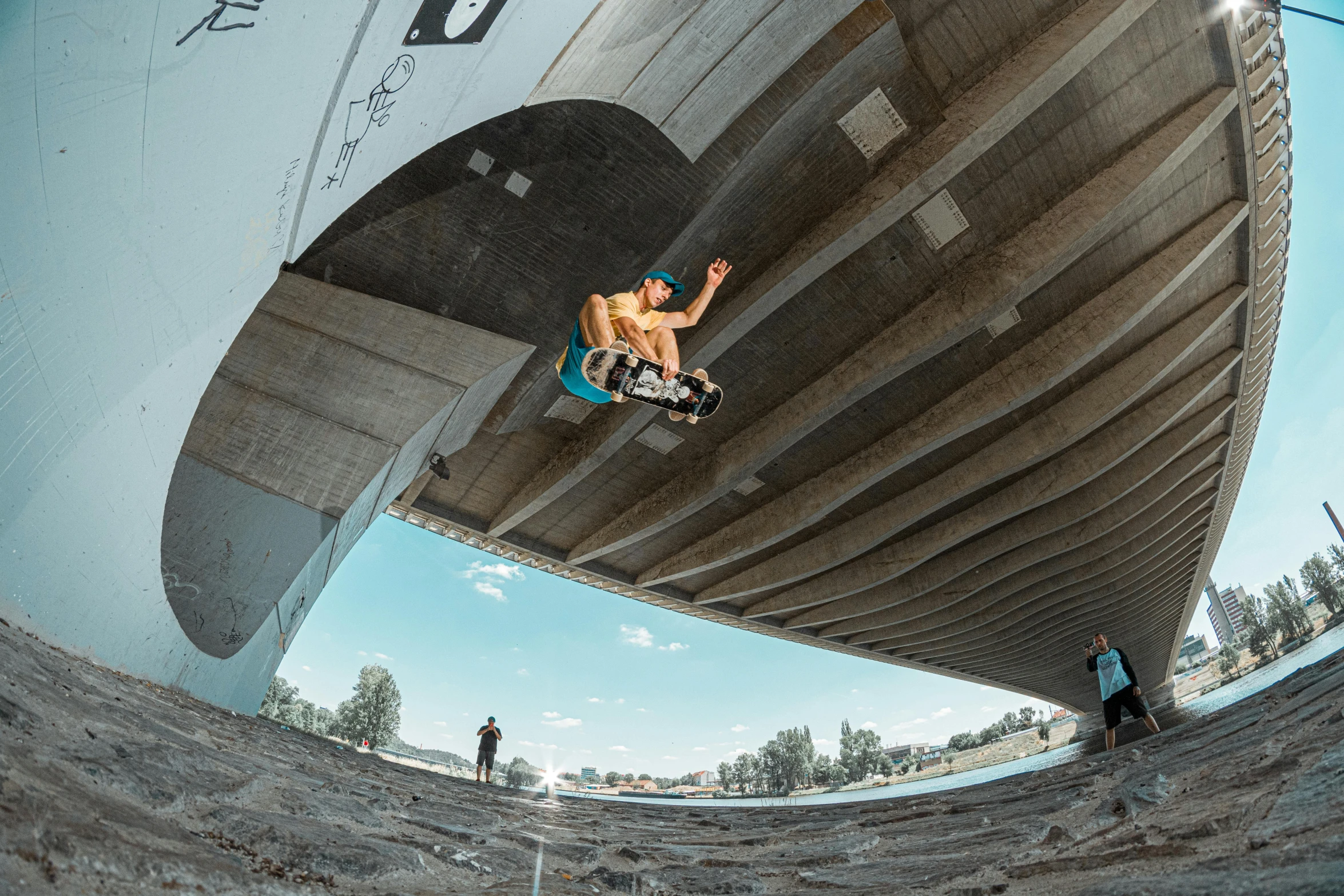 a man flying through the air while riding a skateboard, by Tom Bonson, unsplash contest winner, graffiti, sitting under bridge, very wide view, climber, lachlan bailey