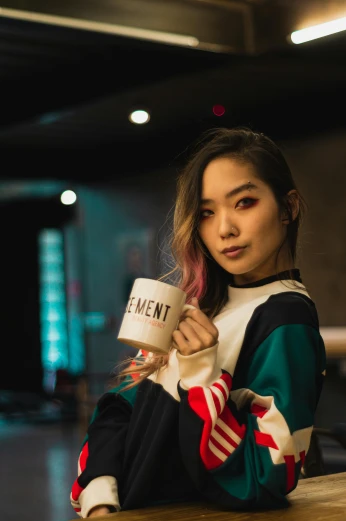a woman sitting at a table with a cup of coffee, a portrait, inspired by Wen Jia, trending on pexels, portrait of kpop idol, concert, woman in streetwear, promotional image