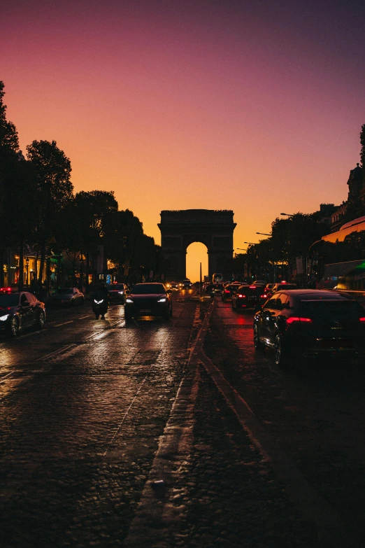 a street filled with lots of traffic next to tall buildings, by Raphaël Collin, pexels contest winner, neoclassicism, arc de triomphe full of graffiti, evening sunset, busy wet street at night, sun down