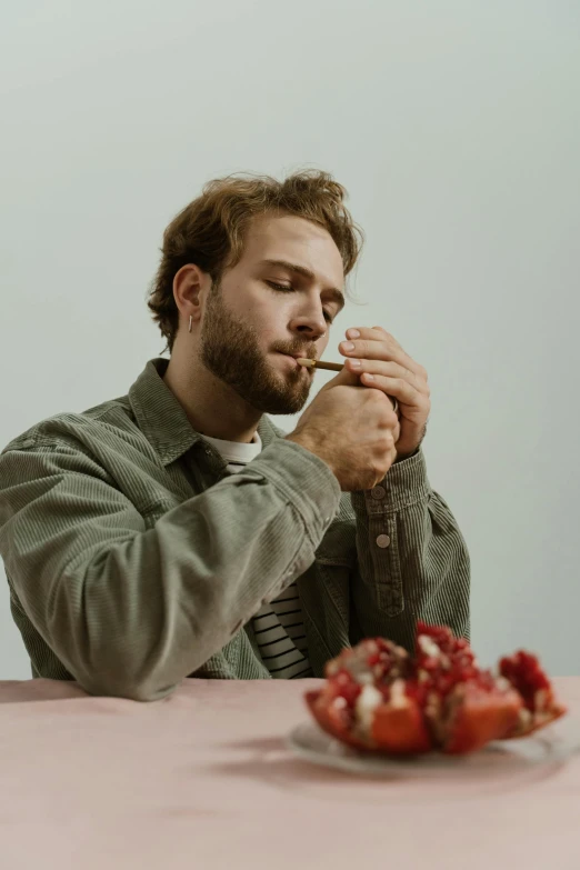 a man sitting at a table with a plate of strawberries, an album cover, trending on pexels, thoughtful pose, smokes, liam, profile pic