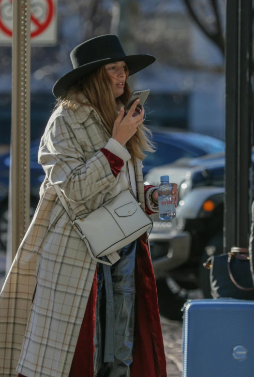 a woman walking down a street talking on a cell phone, nina agdal, black stetson and coat, flannel, candid