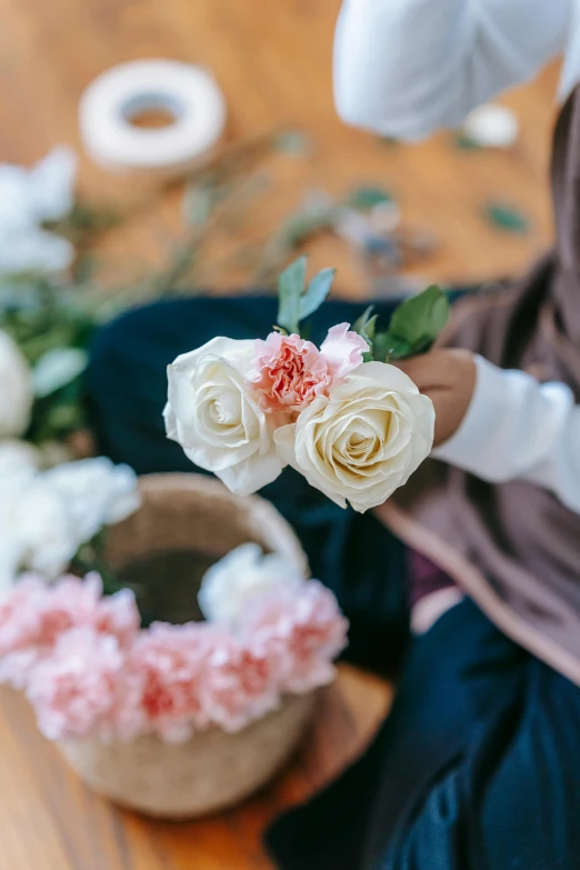 a woman sitting on the floor holding a bunch of flowers, inspired by Li Di, trending on unsplash, renaissance, detail shot, islamic, hand on table, rose crown
