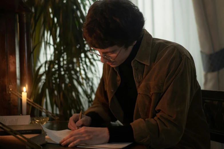 a man sitting at a table writing on a piece of paper, joe keery, ignant, russian academic, charles bowater