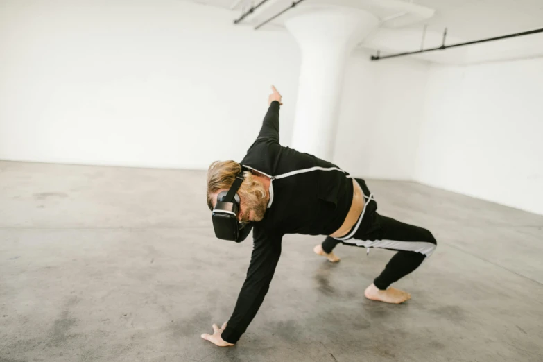 a woman doing a handstand pose in a white room, a hologram, unsplash, interactive art, vr helmet on man, wearing fitness gear, casey cooke, head tilted down