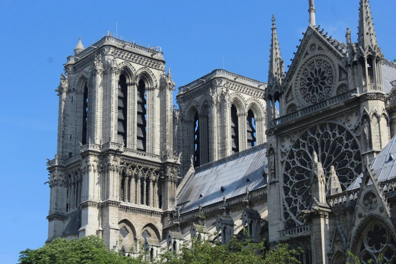 a very tall cathedral with a clock on it's side, flying buttresses, épaule devant pose, seen from afar, parapets