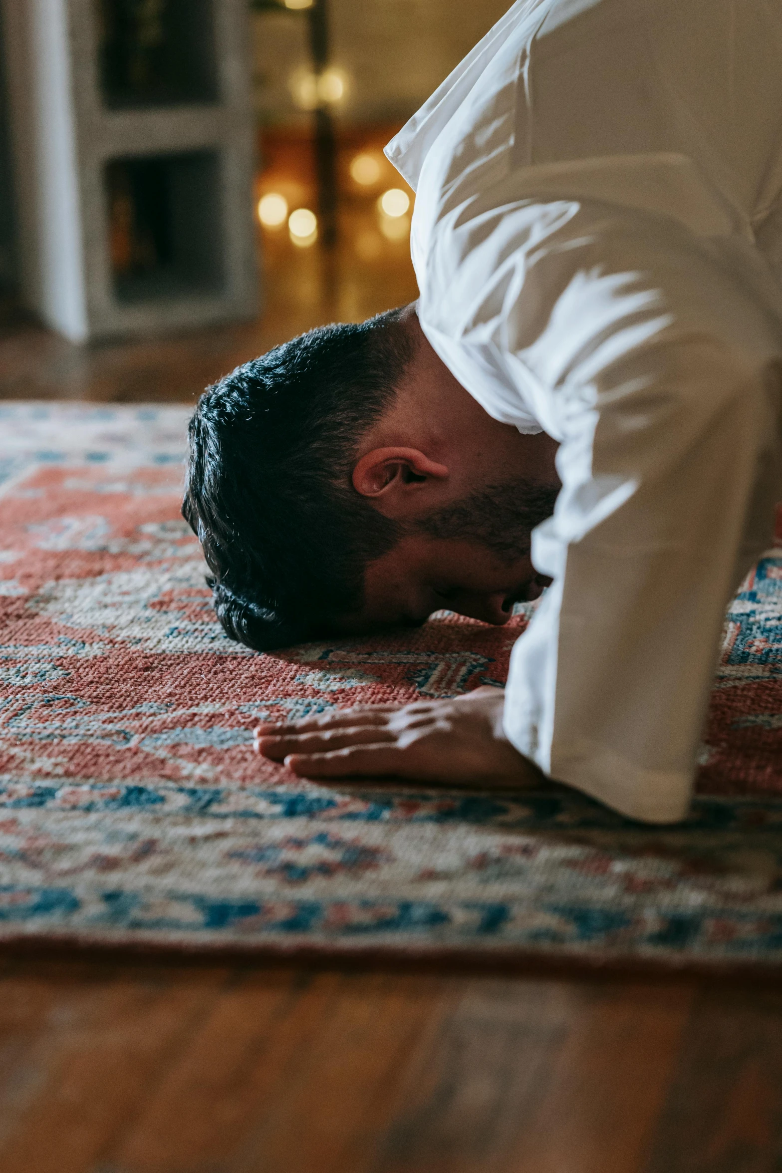 a man is doing a handstand on a rug, by Carey Morris, hurufiyya, kneeling in prayer, indoor setting, a cozy, muslim