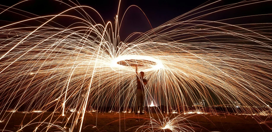 a man standing on top of a lush green field, a stipple, pexels contest winner, kinetic art, sparklers, dancing around a fire, spiraling, lighting her with a rim light