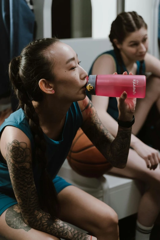 a woman sitting on a bench drinking from a water bottle, pexels contest winner, wearing basketball jersey, of taiwanese girl with tattoos, chun li at the gym, pink skin