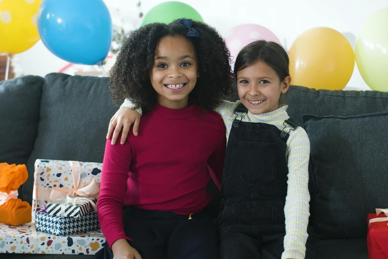 a couple of young girls sitting on top of a couch, by Alice Mason, pexels, at a birthday party, mixed race, balloons, schools