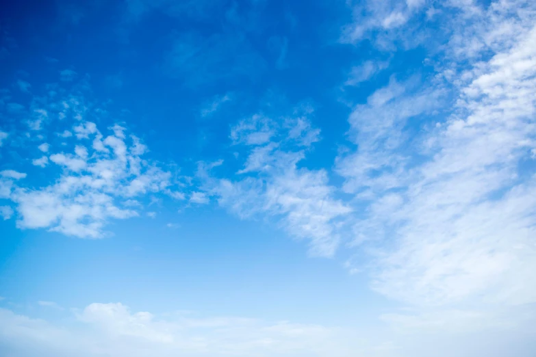 a man riding a surfboard on top of a sandy beach, an album cover, unsplash, minimalism, blue sky with a few clouds, looking upwards, layered stratocumulus clouds, panorama view of the sky