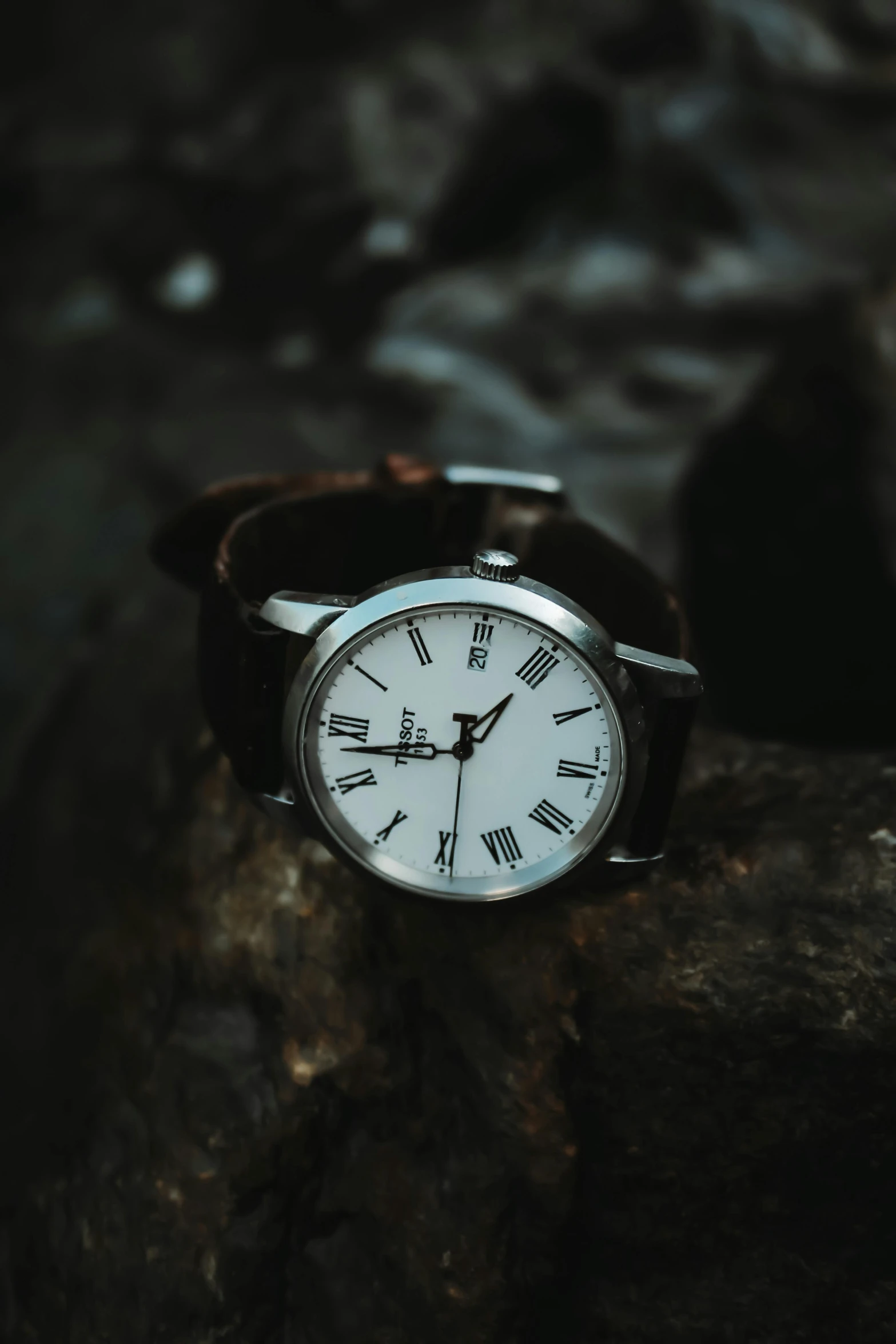 a close up of a wrist watch on a rock, trending on pexels, modernism, roman setting, dark brown white green colours, white: 0.5, analog photo