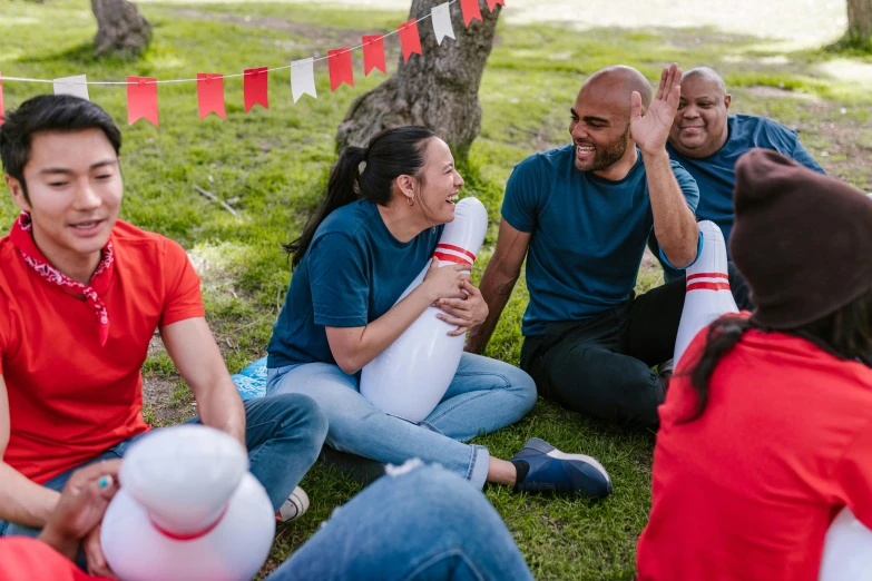 a group of people sitting on top of a grass covered field, holding a balloon, head bent back in laughter, red and white color theme, patriotic