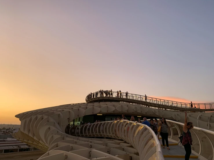 a group of people standing on top of a bridge, inspired by Zha Shibiao, unsplash contest winner, art nouveau, sunset + hdri, mini amphitheatre, seville, parametric structure