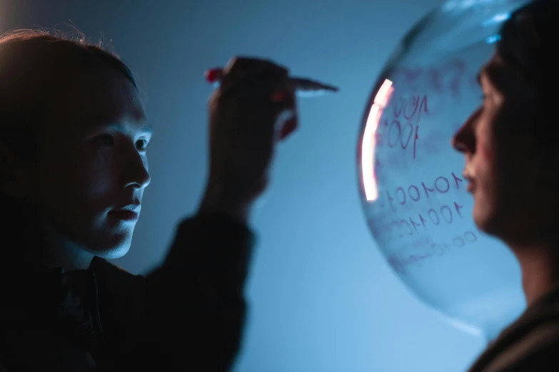 a close up of a person writing on a balloon, a hologram, by Adam Marczyński, portrait of a female pathologist, cinematography photo, promo material, light source from the left