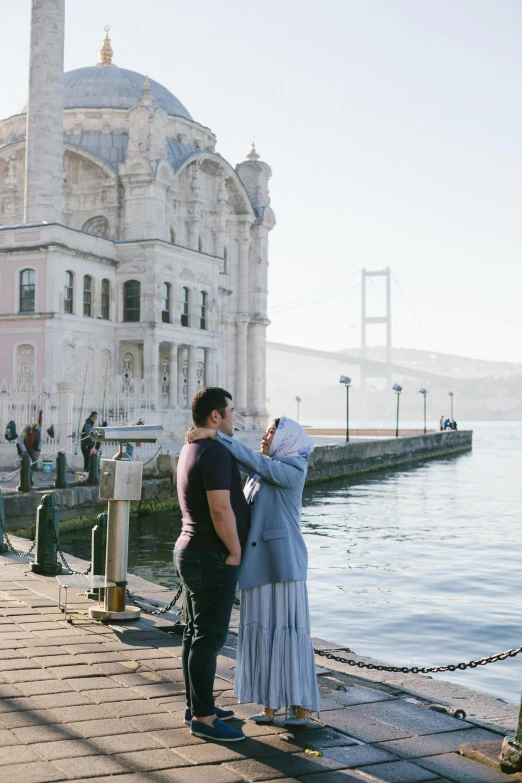 a man and a woman standing next to a body of water, a picture, inspired by Nadim Karam, pexels contest winner, hurufiyya, ottoman sultan, raising between the buildings, kissing together, full body image