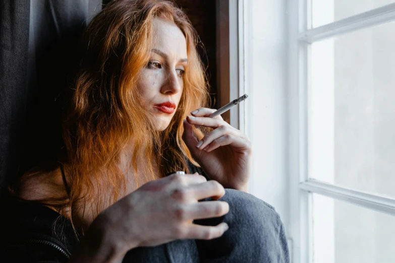 a woman sitting on a window sill smoking a cigarette, a portrait, trending on pexels, ( redhead, clinically depressed, sydney hanson, sitting in a lounge